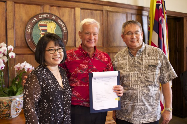 Honolulu Mayor Kirk Caldwell stands in between Haseko Vice President Sharene Tam (left) and Executive Vice President Raymond Kanna (right) after signing bills that allow  Haseko to build a recreational lagoon instead of a marina at the company’s Hoakalei development in Ewa.