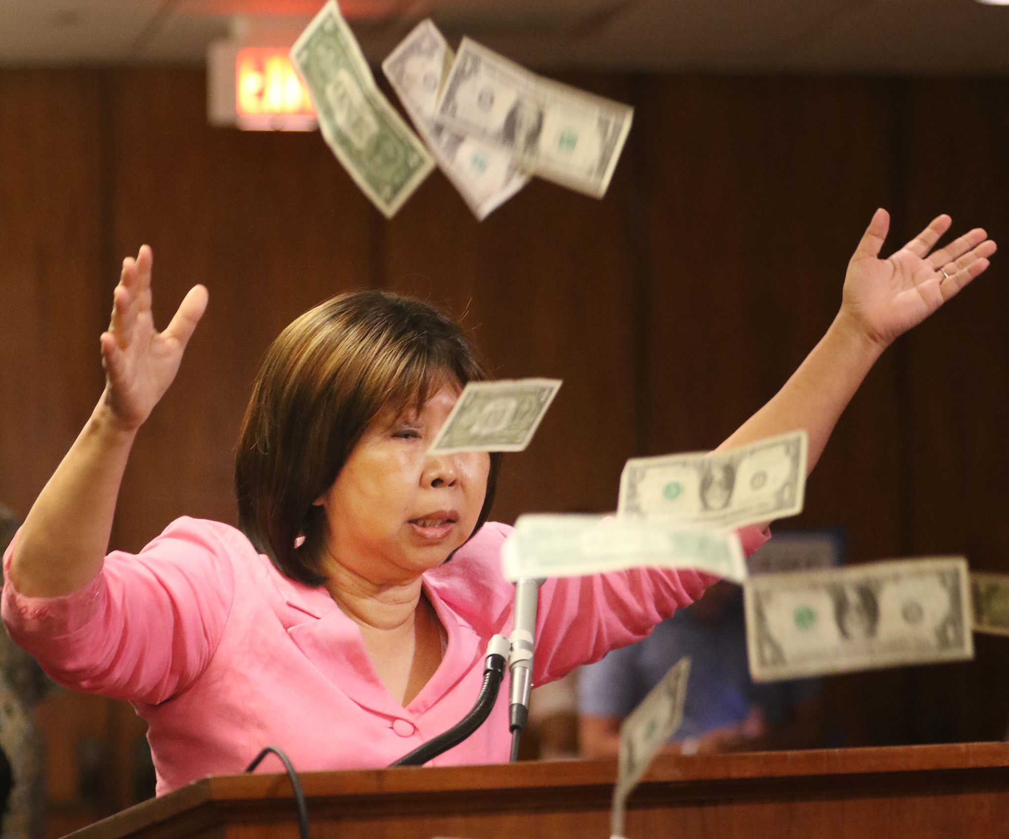 After testifying during WAM hearing Choon James tosses a hand full of dollar bills into the air at the Capitol auditorium.