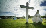 Guam Holy Cross Catholic Cemetery with a partially buried figure of Mary.