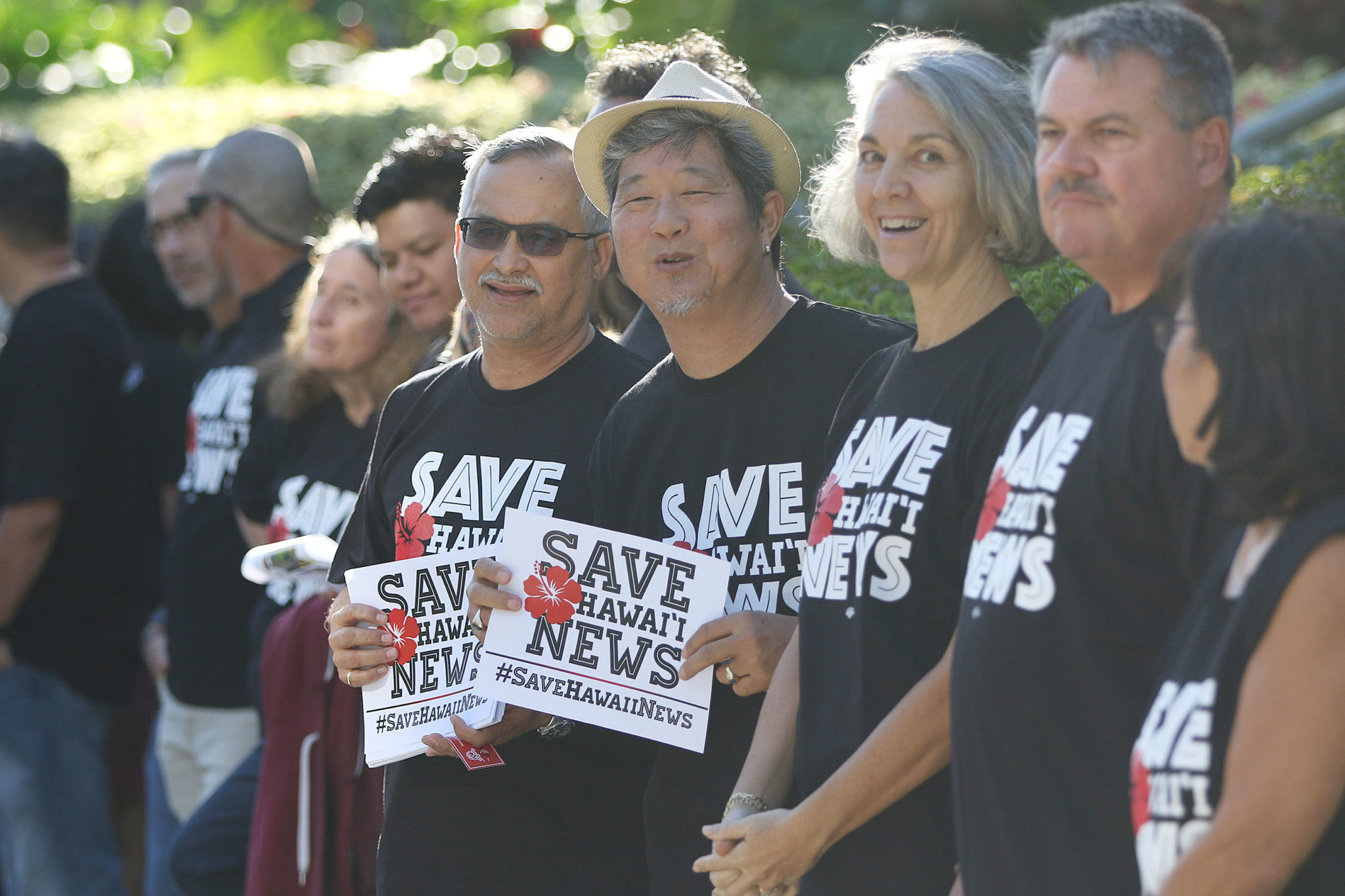 Star Advertiser staffers Rob Perez, left and right, Bryant Fukutomi hold signs Save Hawaii News outside the Honolulu Star Advertiser offices.