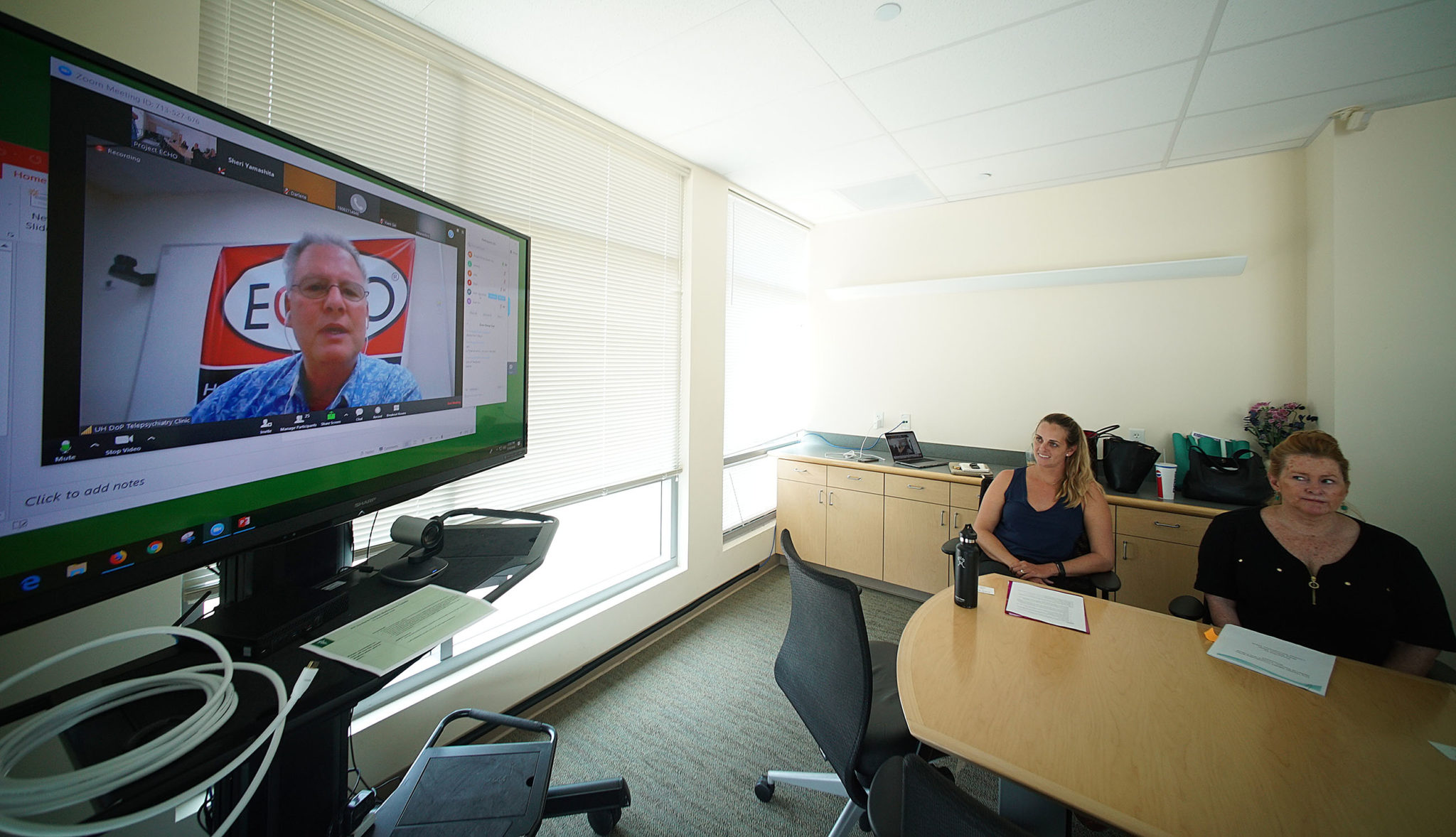 Left, Lindsey Kaumeheiwa, Dept of Health Expert Project Coordinator and right, Hawaii Substance Abuse Coalition, Expert Referral Coordinator Bebe Bainum speak to a group of folks on the screen at left at UH Medical School located in Kakaako.