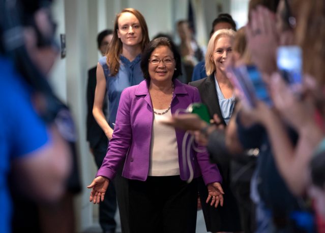 Sen. Mazie Hirono, D-Hawaii, flanked by Sarah Burgess, left, an alumnae of the Holton Arms School, and Sen. Kirsten Gillibrand, D-N.Y., right, is applauded by demonstrators as they arrive to speak to reporters in support of professor Christine Blasey Ford, who is accusing Supreme Court nominee Brett Kavanaugh of a decades-old sexual attack, during a news conference on Capitol Hill in Washington, Thursday, Sept. 20, 2018. Christine Blasey Ford was a student at the Holton Arms School, a Maryland all-girls school, in the early 1980s. (AP Photo/J. Scott Applewhite)