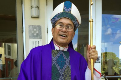 FILE - In this November 2014 file photo, Archbishop Anthony Apuron stands in front of the Dulce Nombre de Maria Cathedral Basilica in Hagatna, Guam. Guam's Catholic church announced Wednesday, Nov. 7, 2018 that it will file for bankruptcy _ a move that lawyers say will allow the archdiocese to avoid trial in dozens of lawsuits alleging child sexual abuse by priests and move toward settlements. The U.S. territory, where almost everyone is Catholic, has been ripped apart by claims the archbishop and other priests abused children. Apuron has denied allegations he molested multiple altar boys. (AP Photo/Grace Garces Bordallo, File)