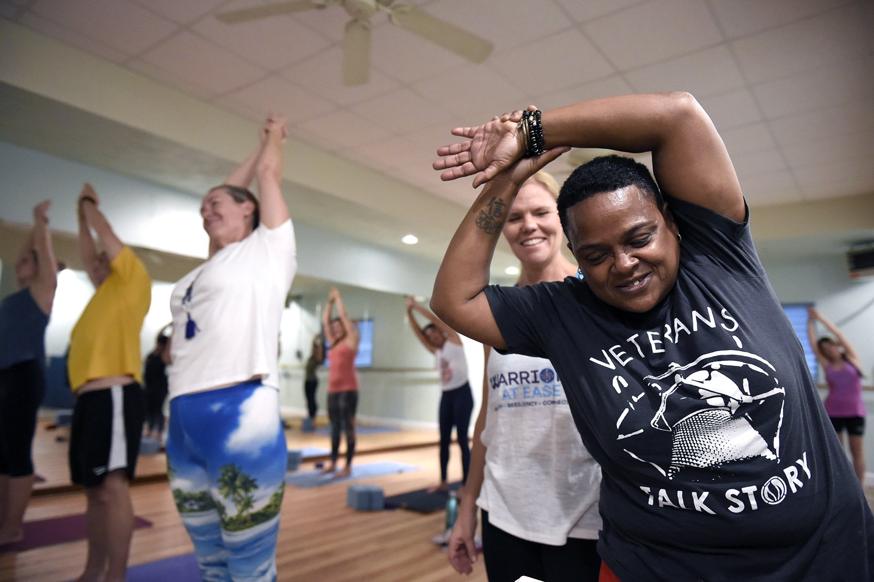 Cyndi Lee smiles while stretching as Susan Alden looks on during a yoga class created to help US military Veterans cope with PTSD called Warriors At Ease at the Bella Kai Yoga Studio in Kailua, Wednesday, November 7, 2018. (Civil Beat photo Ronen Zilberman)