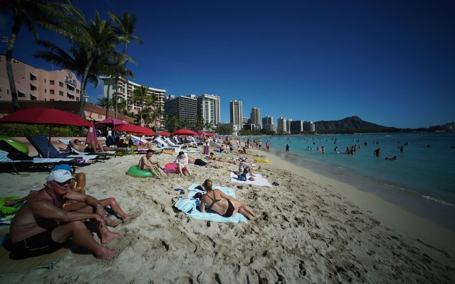 Visitors to Oahu’s Waikiki Beach with Diamond Head in the background.