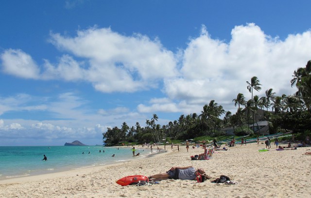 FILE - This Oct. 29, 2013 file photo shows people at Lanikai Beach, a popular neighborhood for vacation rentals, in Kailua, Hawaii. Hawaii says a judge should compel Airbnb to hand over 10 years of receipts and other documents from its hosts because the home-sharing platform has acknowledged that hosts aren't fully complying with state tax laws. A hearing is scheduled for Thursday, Feb. 8, 2019. (AP Photo/Audrey McAvoy, File)