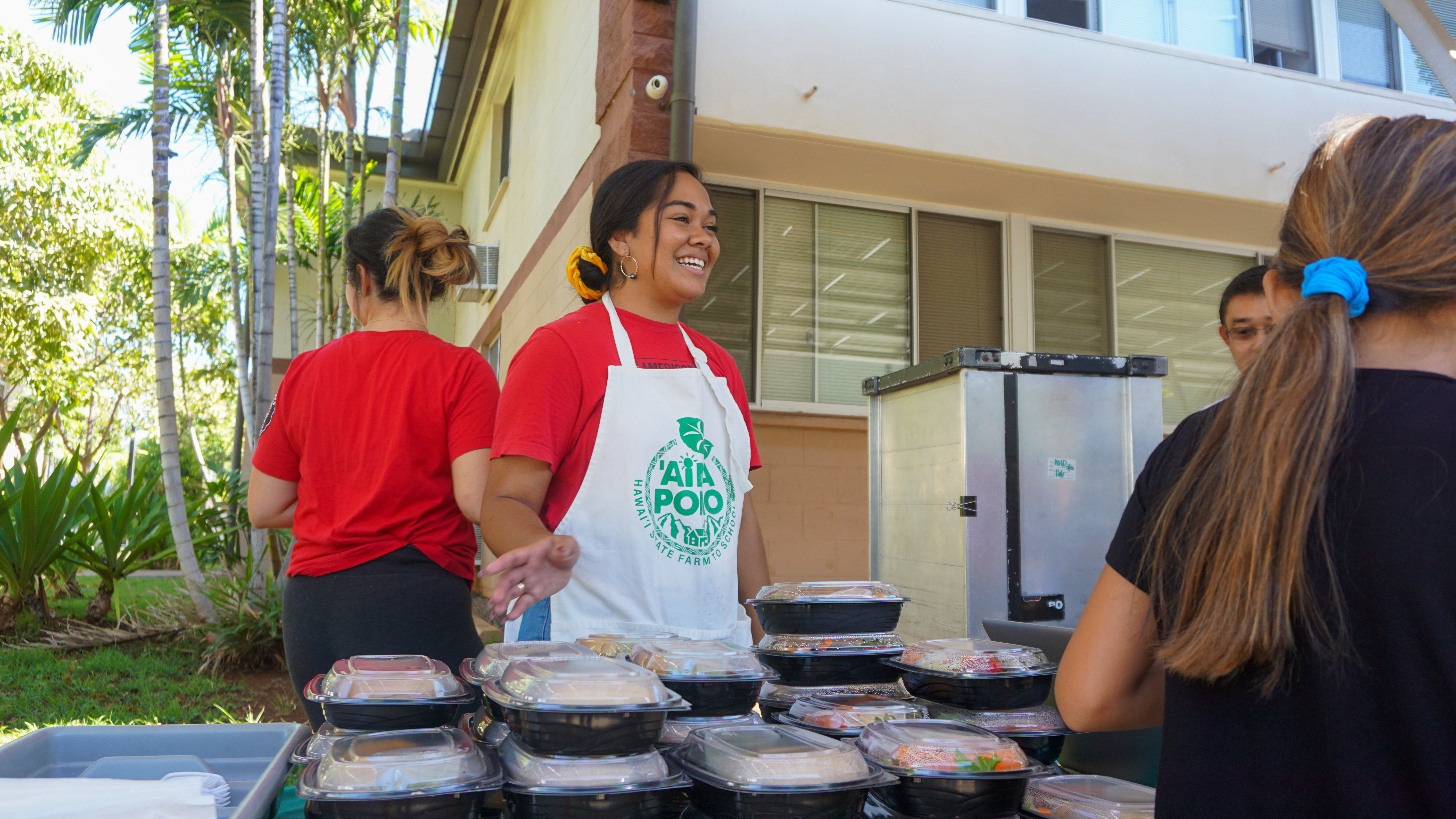 Ruth Kaeo smiles at kids as they pass through the free lunches line outside of Hale Wai Vista.