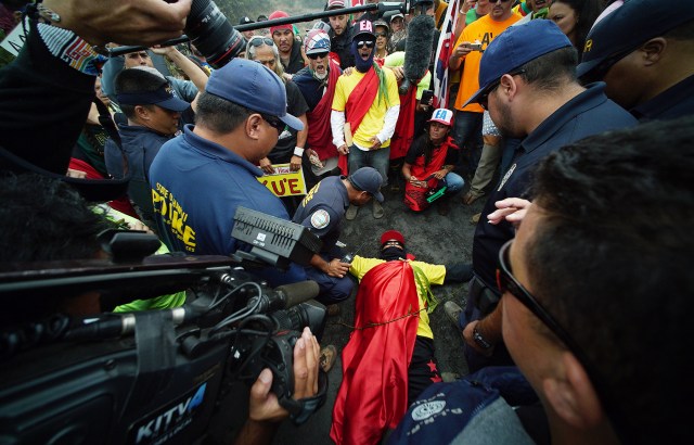 Mauna Kea supporters right hold their line as left, DLNR law enforcement officers tell them to clear the road to allow their vehicles to make the ascent to the summit. One demonstrator decided not to move and instead laid on the ground only to be arrested within minutes. 24 june 2015. photograph Cory Lum/Civil Beat