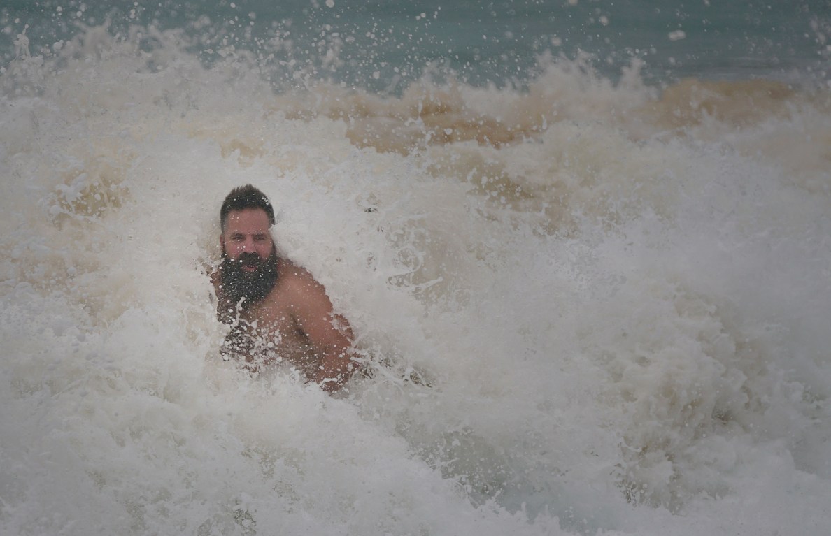 Visitors ignore signs and lifeguards warnings to venture in dangerous shorebreak at Sandy Beach.