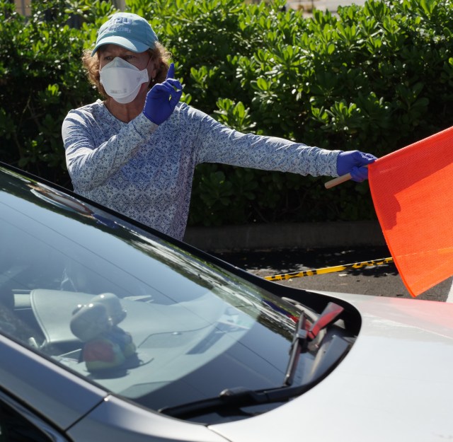 A volunteer nurse practitioner Kari Wilhite helps direct the constant flow of traffic at the drive through COVID-19 test site at the Kaka'ako Waterfront Park in Honolulu, HI, Sunday, March 29, 2020. (Ronen Zilberman photo Civil Beat)