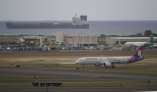 Hawaiian Airlines aircraft fronting an Oil tanker offshore the Daniel K. Inouye International Airport, Reef runway.