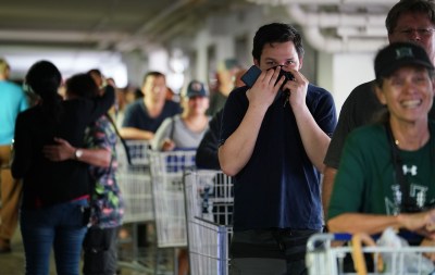 Jay Nordyke holds his shirt over his face wil standing in line with his dad, Thomas Nordyke in the parking lot of Sams Club. The lines snaked from the entrance all the way to the far side of the parking lot.