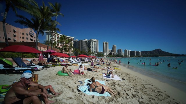 Visitors to Oahu’s Waikiki Beach with Diamond Head in the background.