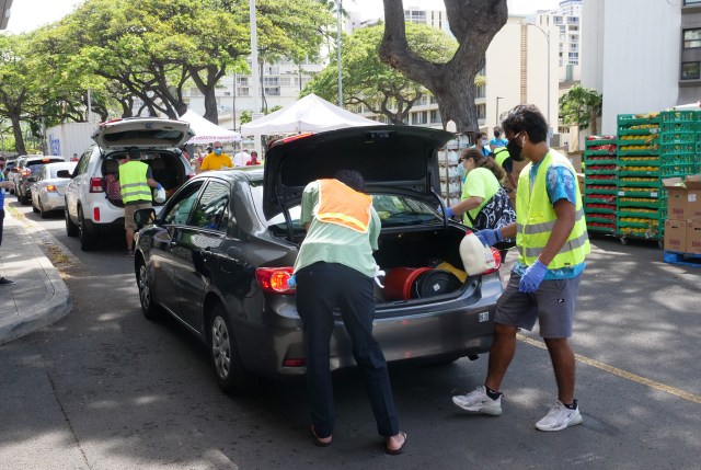 Volunteers load emergency food donations into the trunks of waiting cars at the drive-through distribution event hosted at the Ala Moana Center on Saturday, April 11, 2020, in Honolulu, HI. Milk, bread, and eggs were donated by The Salvation Army Hawaiian & Pacific Islands, Hawaii State VOAD, along with 5,000 lbs of Maui potaties donated by Chad & Stephanie Buck. (Ronen Zilberman photo Civil Beat)