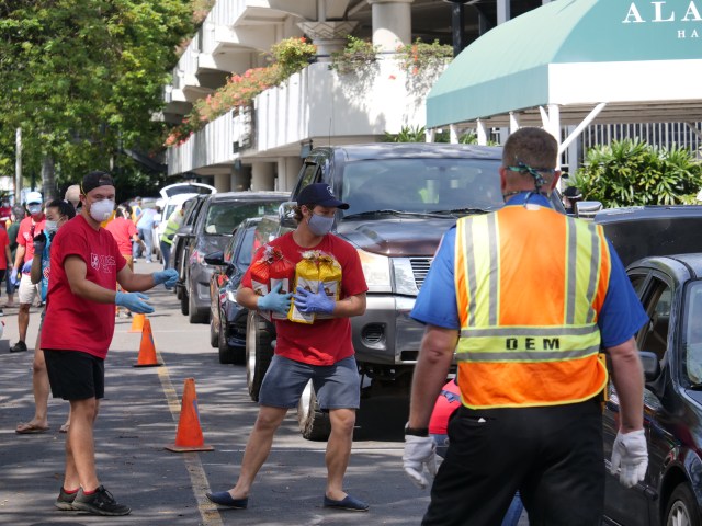 Volunteers load milk, eggs, bread, and potatoes into the waiting cars of those in need who showed up in droves to the Ala Moana Center for emergency food pick-up on Saturday, April 11, 2020, in Honolulu, HI. The Salvation Army Hawaiian & Pacific Islands, Hawaii State VOAD, and private citizens Chad & Stephanie Buck worked together to offer the Easter weekend drive-through food distribution event. (Ronen Zilberman photo Civil Beat)