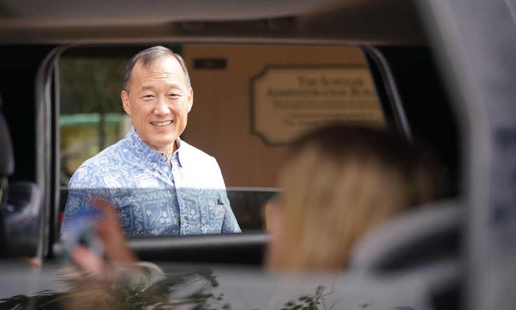 Le Jardin Principal Earl Kim speaks thru car window to kids as parents drive to school to pickup packets.