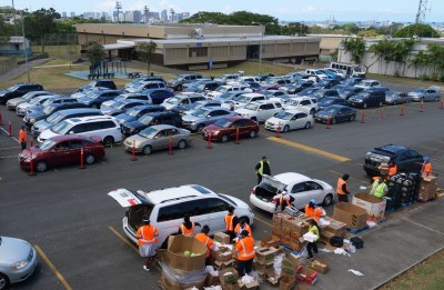 Volunteers from the Lighthouse Outreach Center give out food to Kalihi community members during a distribution event on Thursday, May 14, 2020. Cars snaked for blocks as hundreds of people showed up to receive food donations. (Ronen Zilberman photo Civil Beat)