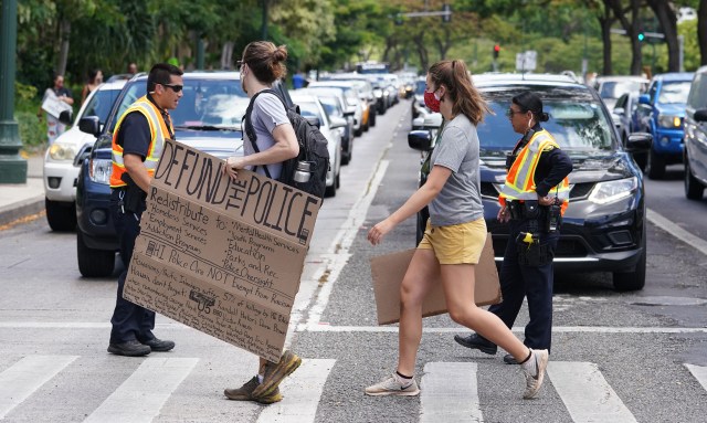 Black Lives Matter marchers cross Ala Moana Blvd with a a’Defund Police’ sign as they head towards the Capitol.