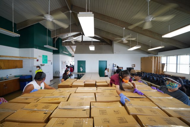 Volunteers stack boxes of food at Papakolea Community Center to be distributed shortly to community members during COVID-19 pandemic.