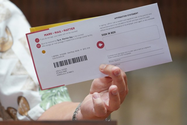 Honolulu City Clerk Glen Takahashi holds a sample Mail in ballot during press conference held at Honolulu Hale.