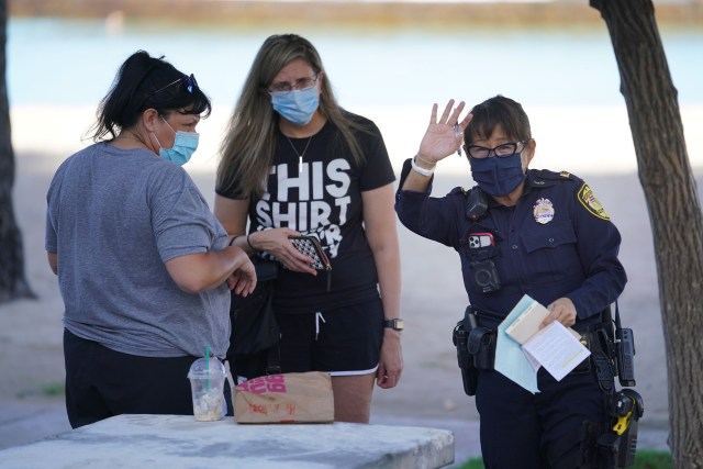 A Honolulu Police Officer cites people at Waikiki Beach. Mayor Caldwell recently closed all parks and beaches due to a spike in COVID-19 cases on Oahu. August 31, 2020