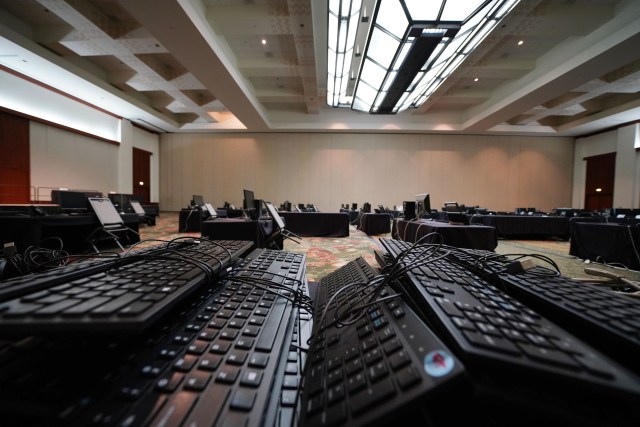 Pile of computer keyboards in an empty Hawaii Convention Center ballroom next to a operational Department of Health contact tracing ballroom with staff. Governor Ige earlier held a press conference in this room.