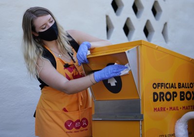 Voter Service Center worker Brooke Webb disinfects the official ballot collection box outside Honolulu Hale. August 6, 2020
