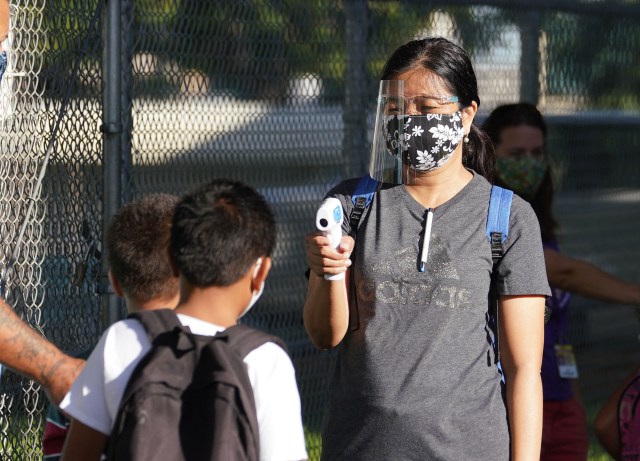 Kauluwela Elementary staff uses thermometer on arriving students during COVID-19 pandemic. August 17. 2020