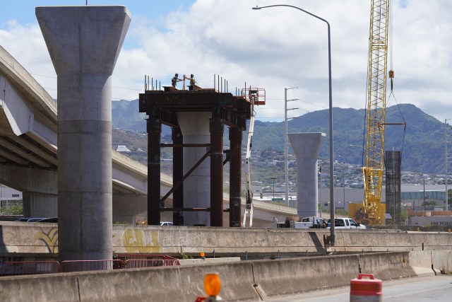 Silhouettes of workers high atop rail guideway columns near Middle Street/Keehi area as columns march towards the Honolulu city core. September 17, 2020