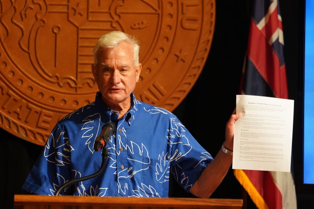 Mayor Kirk Caldwell holds some of the documents outlining the partial reopening of Honolulu on thursday.