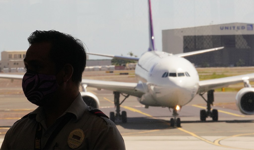 Silhouette of an airport security personnel as an arriving Hawaiian Airlines flight arrives at Daniel K. Inouye International Airport as transpacific travel is beginning to resume from today during COVID-19 pandemic. Passengers are required to have a COVID-19 test before arriving to Hawaii. October 15, 2020