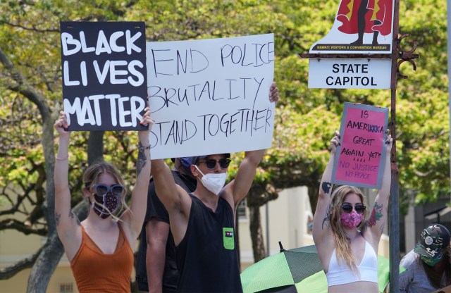 Black Lives Matter supporters hold signs along Beretania Street fronting the Capitol.