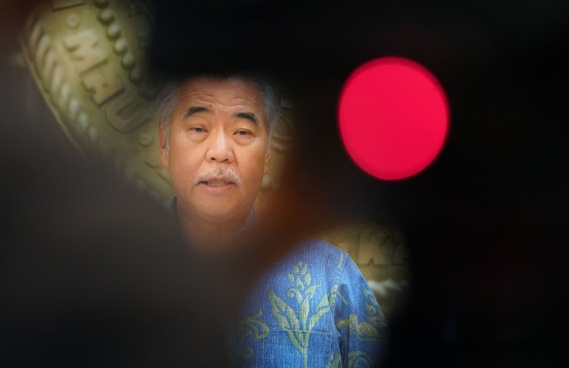 Governor David Ige seen with pool video photographer silhouette in the foreground discusses possible cuts to the state’s budget during COVID-19 pandemic. December 21, 2020