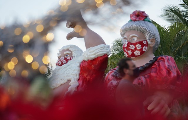 Santa Claus and Mrs. Claus are masked fronting Honolulu Hale holiday decorations during COVID-19 pandemic.