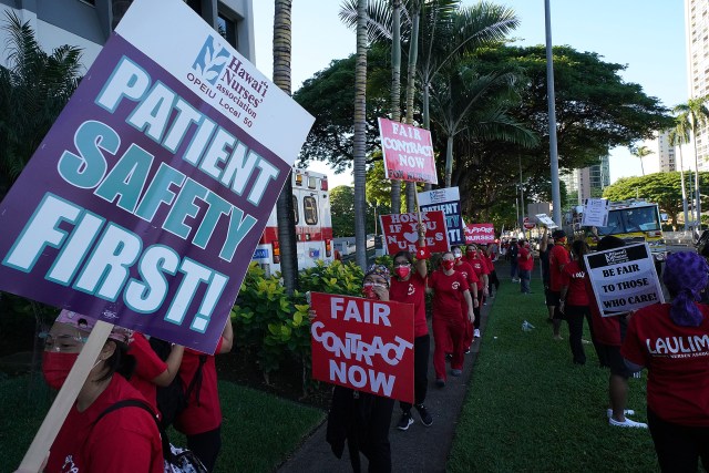 Nurse hold signs protesting fronting the Kapiolani Womens and Childrens hospital.