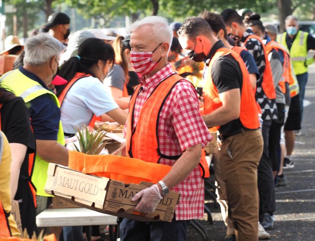Honolulu Mayor Kirk Caldwell works with other volunteers pack boxes of food for the last mass distribution event of the year at Aloha Stadium sponsored by the City of Honolulu and the Hawai'i Food Bank, on Friday, December 18, 2020. (Ronen Zilberman photo Civil Beat)