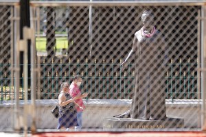 People walk near the Queen Liliuokalani statue as seen thru recenly installed fencing and barriers on the mauka and makai sides of the Capitol. January 14, 2021.