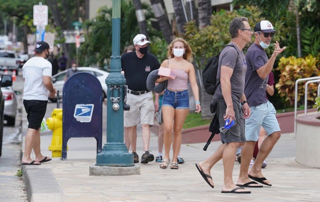 Masked and unmasked visitors stroll along Kalakaua Avenue as more visitors arrive. Saturdays arrivals topped almost 25,000 people. March 24, 2021