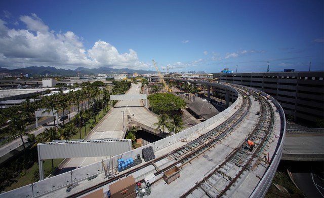 Workers assist in track installation on the rail guideway located at the Daniel K. Inouye International Airport.