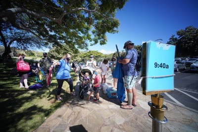 Hanauma Bay visitors stand near a sign that shows entrance appointment times.