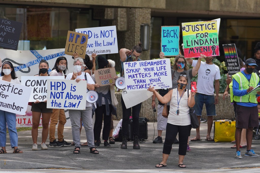 People gather with signs on the opposite corners near District Court.