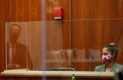 Honolulu police officer Chanel Price, right, listens to questions from prosecuting attorney Christopher Van Marter, seen in a reflection on a plexiglass barrier, in the district courtroom of judge William M. Domingo during the second day of preliminary hearings for three Honolulu police officers in the killing of Iremamber Sykap on Tuesday, July 27, 2021, in Honolulu. (POOL PHOTO/Jamm Aquino/Honolulu Star-Advertiser).