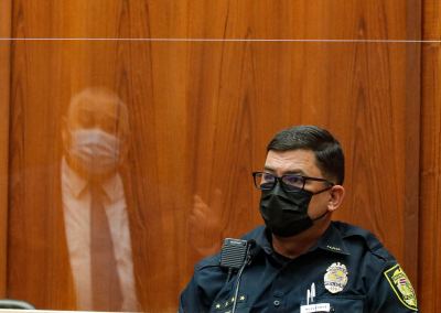 Honolulu police Sgt. Adam Lipka listens to questions from defense attorney Richard Sing, reflected in the plexiglass barrier, in the district courtroom of judge William M. Domingo during the third day of preliminary hearings for three Honolulu police officers in the killing of Iremamber Sykap on Tuesday, July 27, 2021, in Honolulu. (POOL PHOTO/Jamm Aquino/Honolulu Star-Advertiser).