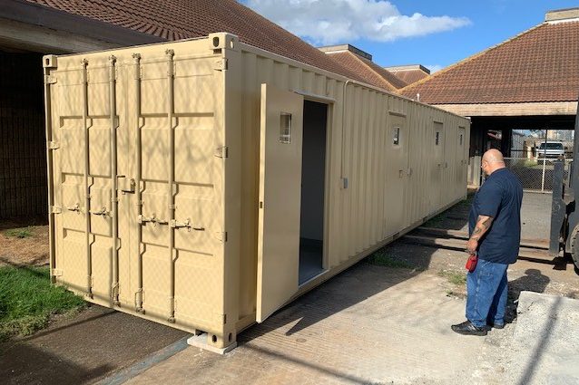 A worker at one of the two container-type isolation units that were delivered to OCCC in December 2020. Each unit has four cells that can be used for quarantine, but the aging electrical system at the jail cannot handle the additional load. Corrections officials are seeking funding to make electrical upgrades.