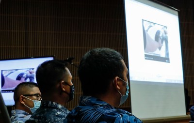 Honolulu police officers Geoffrey Thom, left, Christopher Fredaluces, and Zackary Ah Nee look at body camera footage on the monitor screen in the district courtroom of Judge William M. Domingo during preliminary hearings for three Honolulu police officers in the killing of Iremamber Sykap on Tuesday, Aug. 17, 2021, in Honolulu. (POOL PHOTO/Jamm Aquino/Honolulu Star-Advertiser).