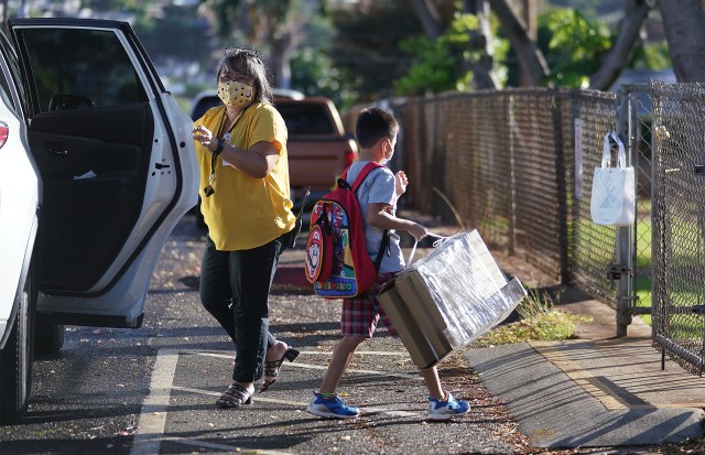 Waialae Elementary Public Charter school staff Melanie Sumida assists with arriving students. Waialae Elementary started last week.