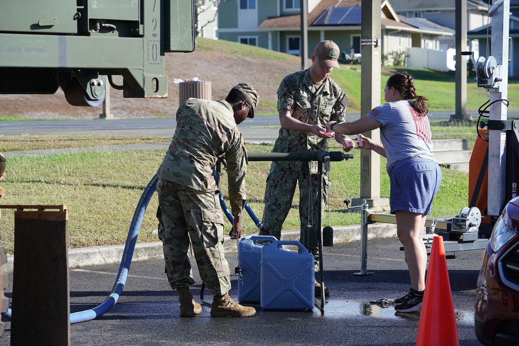 Navy personnel assist residents with filling containers at Halsey Terrace Community Center.