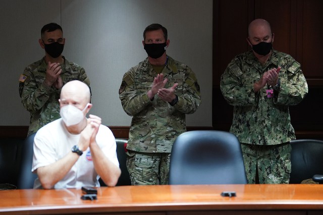 Military personnel and staff applaud after documents were signed in a bried ‘photo op’ held by the US Navy. December 17, 2021