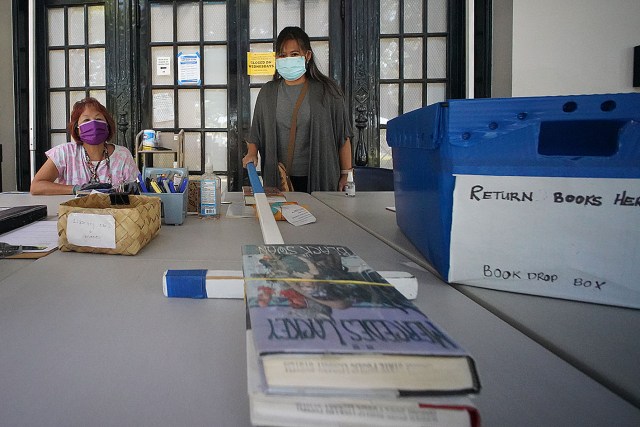 Hawaii State Library workers use a stick to push books to people that borrow books. Workers declined to give their names.