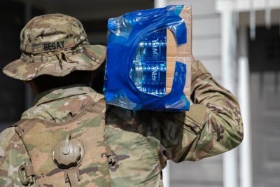 Army caption: Soldiers with 2nd Squadron, 14th Cavalry Regiment, 2nd Infantry Brigade Combat Team, 25th Infantry Division, distribute water door-to-door on December 2, 2021 at Aliamanu Military Reservation, Hawaii.